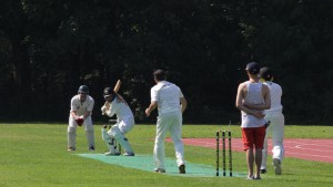 Umpire Bowes in traditional dress, Weston hits to leg and Altmann prepares to run